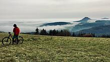 Der Hegau im Nebel: Wie in Watte gepackt schaue die Spitzen einzelner Hegau-Vulkane aus der dichten Wolkendecke. Ein Mountainbiker hat ...
