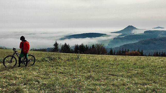 Der Hegau im Nebel: Wie in Watte gepackt schaue die Spitzen einzelner Hegau-Vulkane aus der dichten Wolkendecke. Ein Mountainbiker hat ...