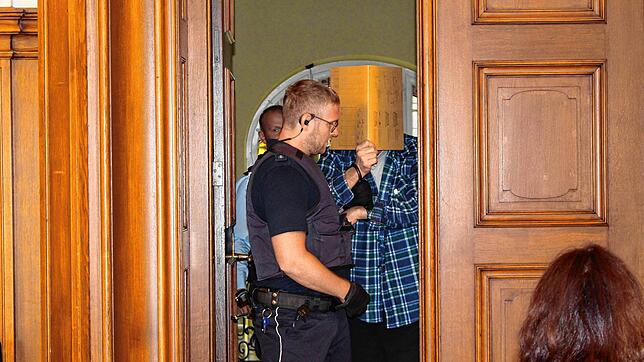 Der Angeklagte wird von einem Justizbeamten in einen Saal des Landgerichts Rottweil geführt. Sein Gesicht verbirgt der 50-Jährige hinter ...
