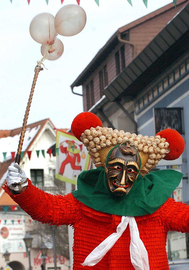 Ein roter Elzacher Schuttig, der mit Schneckenhüsli besetzte Dreizack trägt Wollbollen. Diese Larve ist vom Typ „Fratz“.