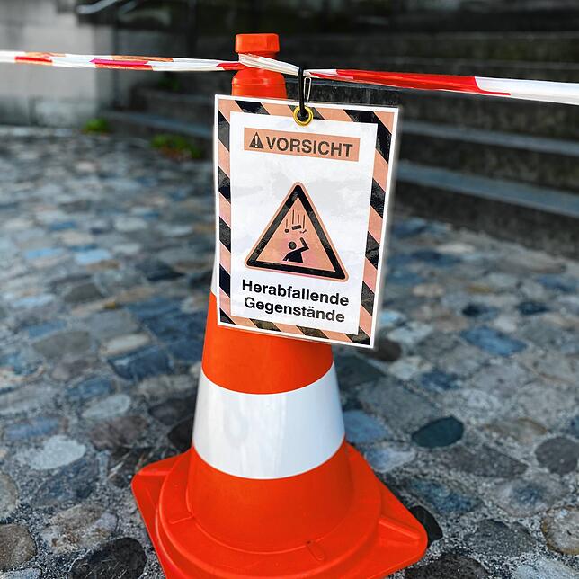 Unten vor dem Münster wird vor herabfallenden Gegenständen gewarnt.