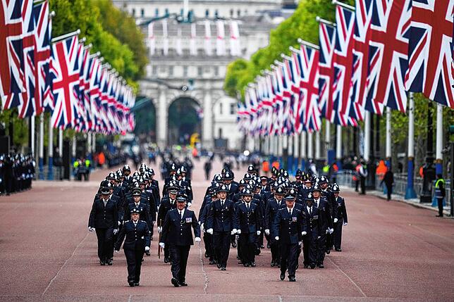 Polizeibeamte gehen vor der Staatsakt zur Beisetzung von Königin Elizabeth II. über die Prachtstraße The Mall.