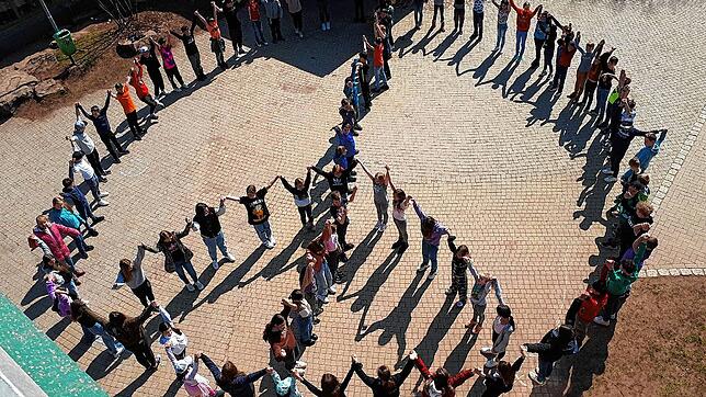 Die Schüler der Realschule stellen sich in Form des Peace-Zeichens auf dem Schulhof auf.