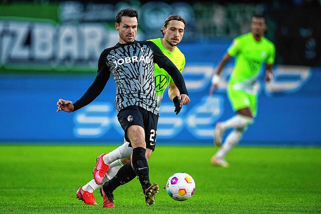 Freiburgs Nicolas Höfler (l) spielt gegen Wolfsburgs Lovro Majer.