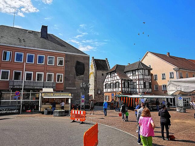 Im großzügigen Radius und auf Abstand stellen sich Besucher des Markdorfer Wochenmarktes an, um sich bei Otto‘s Wurstbraterei eine Rote, ...