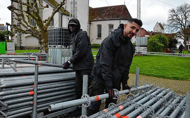 Gemeinsam anpacken: Brimo Conte (rechts) und Feras Aboufakaer bereiten den Aufbau des Bühnenbodens am Marktplatz vor.