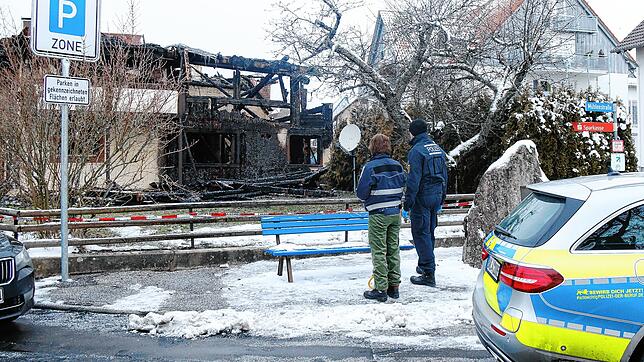 In der Herdstraße in Mönchweiler stehen am Freitag, 27. Januar, ermittelnde Polizeibeamte vor der Brandruine.