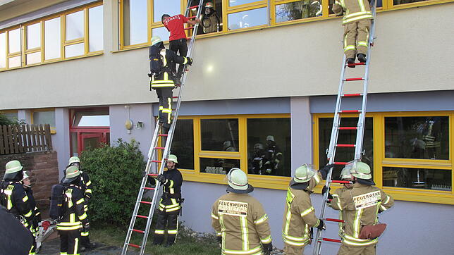 Über Leitern holten die Wehrmitglieder die Schüler aus den Klassenzimmern. Rechts im Bild ist die Wehr aus Heinstetten im Einsatz, links ...