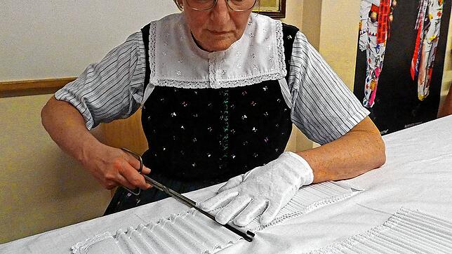 Mit der Brennschere formt Heidi Merkle Falten in die gestärkte Baumwollbahn. Bild: Alfred Moosmann/Heimathaus