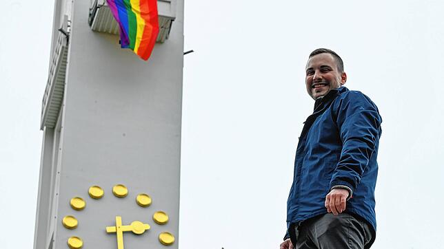 Oberministrant Jonas Teige vor dem Kirchturm von St. Meinrad, an dem die Minstanten aus Protest eine Friedensfahne in den Farben des ...