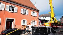 Ein Autokran hebt den Narrenbaum über das Dach zum Dachfenster des Treppenhauses.