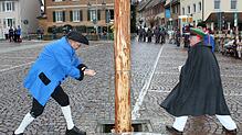 Narrenvater &bdquo;Hubert I.&ldquo; Rössler und Narrenbolizei Michael Bauer sägen am Stamm des Narrenbaums. Im Hintergrund links spannen ...