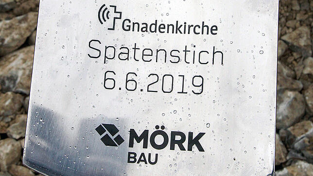Diesen Spaten übergibt Daniel Kurzius von der Firma Mörk zum Baustart an Tobias Walderich von der Gnadenkirche.