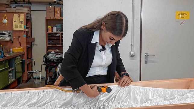Auch handwerkliche Aufgaben gehören zu Jacqueline Muzzis Beruf. Hier schlägt sie einen Sarg aus, bereitet also den Sarg mit einem Stoff vor.