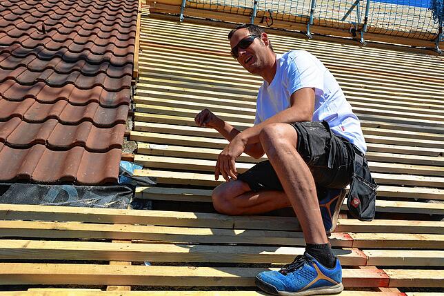 Zimmermann Benjamin Wurster erklärt den Unterschied zwischen alter und neuer Dachdeckung.