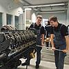 Die beiden Auszubildenden Philipp Klein (links) und Luca Wiedmann stellen bei MTU einen der kleinsten Motoren des Unternehmens vor.