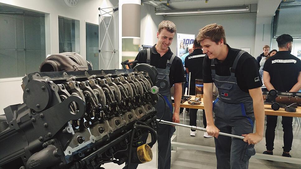 Die beiden Auszubildenden Philipp Klein (links) und Luca Wiedmann stellen bei MTU einen der kleinsten Motoren des Unternehmens vor.