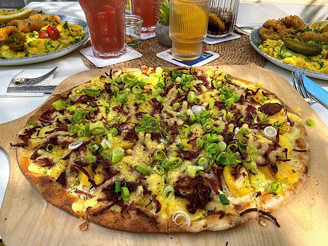 Der Landfrauen-Flammkuchen mit Kartoffeln, Käse, Speck und karamellisierten Zwiebeln.