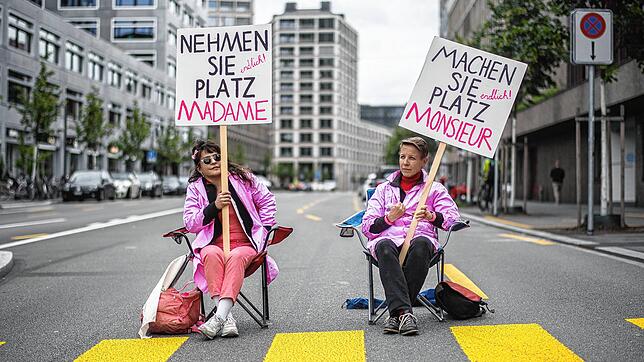 Zwei Frauen halten bei einer Sitzblockade im vergangenen Sommer Schilder mit Protestslogans hoch.