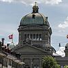 Die Schweizer Nationalfahne weht auf den Kuppeln des Bundeshauses in Bern. Hier wird im Herbst die Entscheidung fallen, ob die Polizei ...