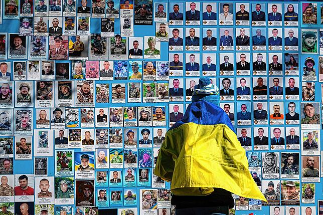 Eine Frau neben einer Gedenkmauer für gefallene ukrainische Soldaten: Die Front der Ukraine kämpft mit Nachschubproblemen.
