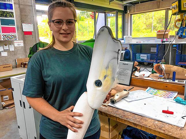 Jana Lehmann hält eine Prothese in der Hand. Dieses Modell hat einen elektrischen Motor, auf dem Bild auf dem Tisch. Testschafte sind ...
