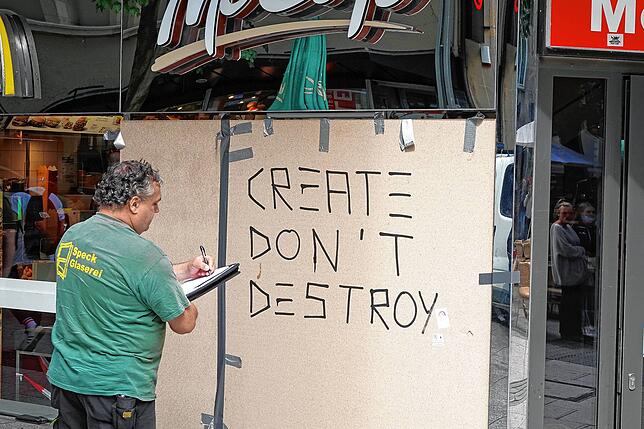Der Mitarbeiter eines Glaser-Betriebs bereitet den Austausch einer beschädigten Scheibe vor. Jemand hat die Mahnung „Create ...