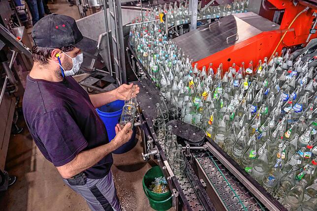 In der Flaschenwaschmaschine wird das Leergut gründlich gereinigt. Das Bild zeigt Mitarbeiter Klaus Auer bei der Überprüfung einer Flasche.