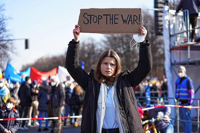 Klimaaktivistin Luisa Neubauer hält ein Schild „Stop the war!“ vor der Demonstration.
