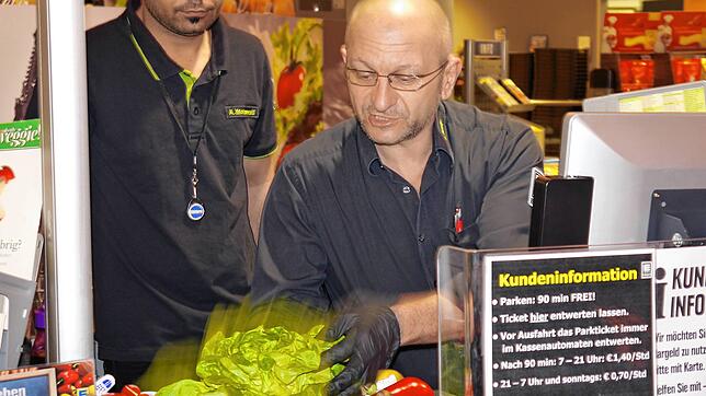 Kassierer Richard Seidl (rechts) arbeitet Aminallah Mohammadi an der Kasse ein.