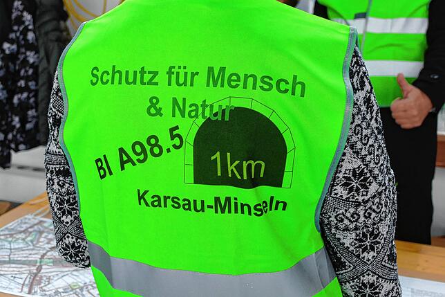 Ein Vertreter der BI A98 Tunnel Karsau-Minseln trägt eine neongrünen Weste und macht auf die Forderung aufmerksam.