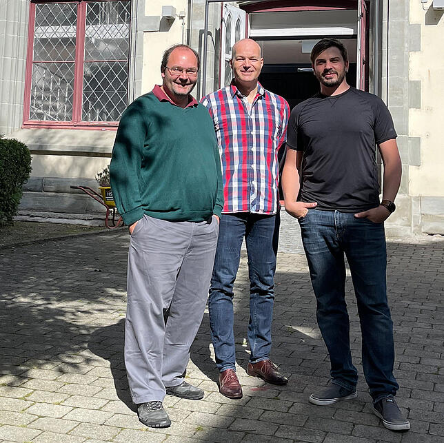 Hauke Hansen (Mitte) als neuer Eigentümer der früheren Stiftskirche St. Johann (im Hintergrund die markanten Fenster) und seine Mieter ...