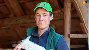 Albert Hahn (35) mit einem Lamm vor seinem Stall in Peterzell.