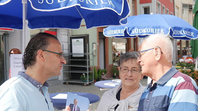 Der OB-Kandidat im Gespräch mit Bürgern: Gaetano Crsitilli positioniert sich am Aktionsstand des SÜDKURIER im Gespräch mit diesem Ehepaar.