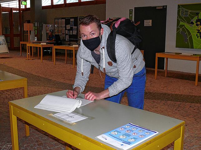 Dominik Brecht trägt sich am Eingang der Uni in die Liste ein.
