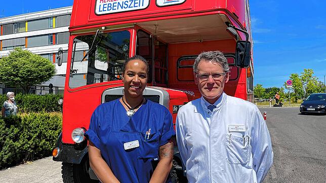 Hubert Kimmig und Krankenschwester Rebecca Katz vor dem Londoner Doppeldeckerbus der Gesundheitsinitiative „Herzenssache Lebenszeit“. ...