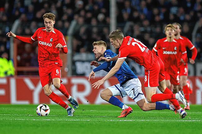 Bielefelds Julian Kania (M) im Kampf um den Ball mit Freiburgs Matthias Ginter (r).