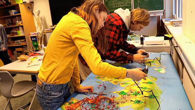 Davina und FSJ-ler Joshua gestalten ein buntes Plakat für den Adventsmarkt des Bildungszentrums. Bild: Martha Weishaar