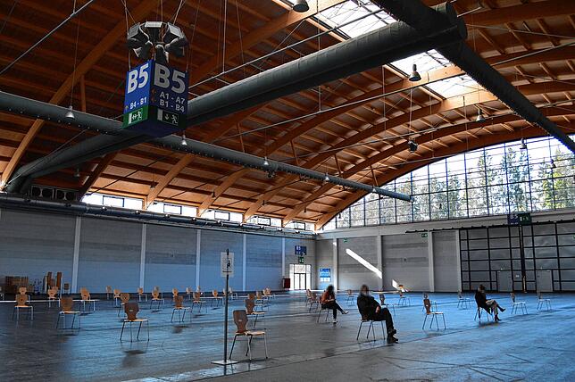 Zahlreiche Stühle mit einem Abstand von etwa 2 Metern sind in der Messehalle aufgestellt. Dieser Bereich dient als Warteraum für die ...