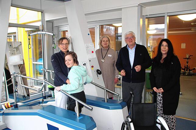 Das Bild zeigt Patientin Verena Gradel mit Betreuerin Anna Wehling auf einem Gangtrainer, dahinter Pflegedirektorin Ina Rathje, Heinz ...