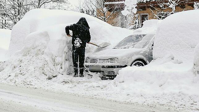 Ein Mann schaufelt sein Auto auf einem Parkplatz in Saalbach aus. Immer mehr Orte sind aufgrund der sehr großen Lawinengefahr nicht mehr ...