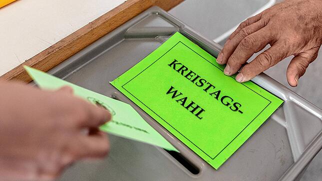 Ein Mann gibt im Wahllokal seinen Stimmzettel zur Kreistagswahl ab. Hier ein Symbolbild.
