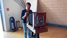 Philipp Güntert, neuer Mitarbeiter im Stadtmuseum Stockach, mit der Originalkamera von Gustav II. Hotz, die auch den Ausstellungsflyer ...