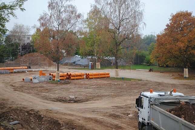 Blick auf die Liegewiese: Dort wo nun die orangefarbenen Rohre liegen, soll später der neue Eingangsbereich des Freibads errichtet werden.