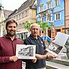 Julian Windmöller, Leiter des Stadtarchivs und -museums, sowie Michael Fritz von Papier Fritz stehen in der Hauptstraße und Windmöller ...