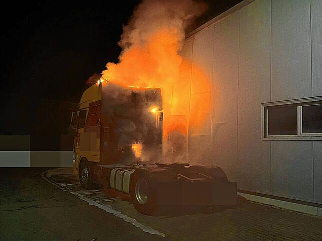 Der Lastwagen steht direkt an der Wand des Firmengebäudes.