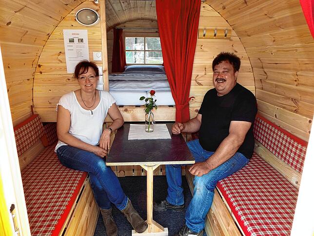 Ehepaar Rita und Andreas Gerspach in einem Fass, das sie ihren Gästen zum Übernachten anbieten.