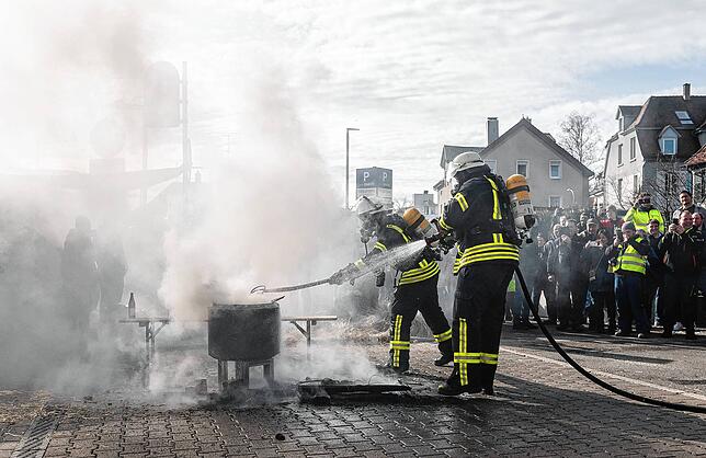 Einsatzkräfte der Feuerwehr löschen ein Feuer, das Demonstranten beim politischen Aschermittwoch in Biberach angezündet haben.