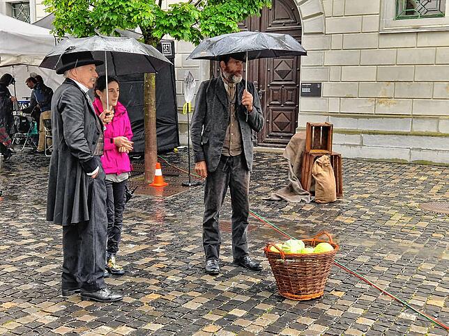 Statisten warten auf dem Klosterhof im Regen auf ihren Einsatz.