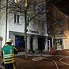 Einsatzkräfte der Feuerwehr stehen am frühen Morgen des 30. Dezembers vor dem ausgebrannten Geschäft in der Karlstraße. (Archivbild)